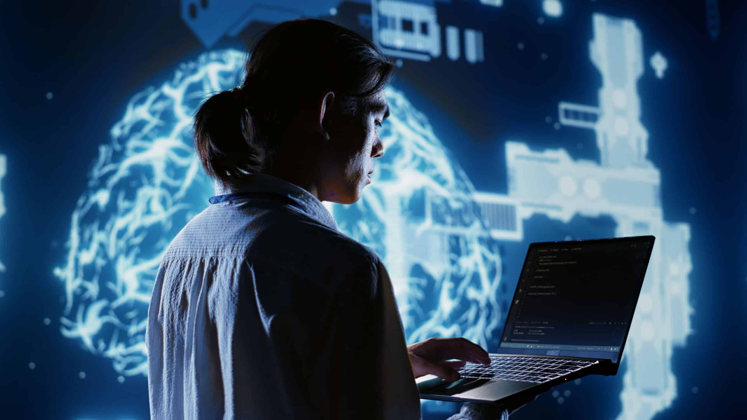 A person with long hair in a ponytail uses a laptop, standing in front of a large glowing digital brain graphic and futuristic interface icons on a dark blue background.